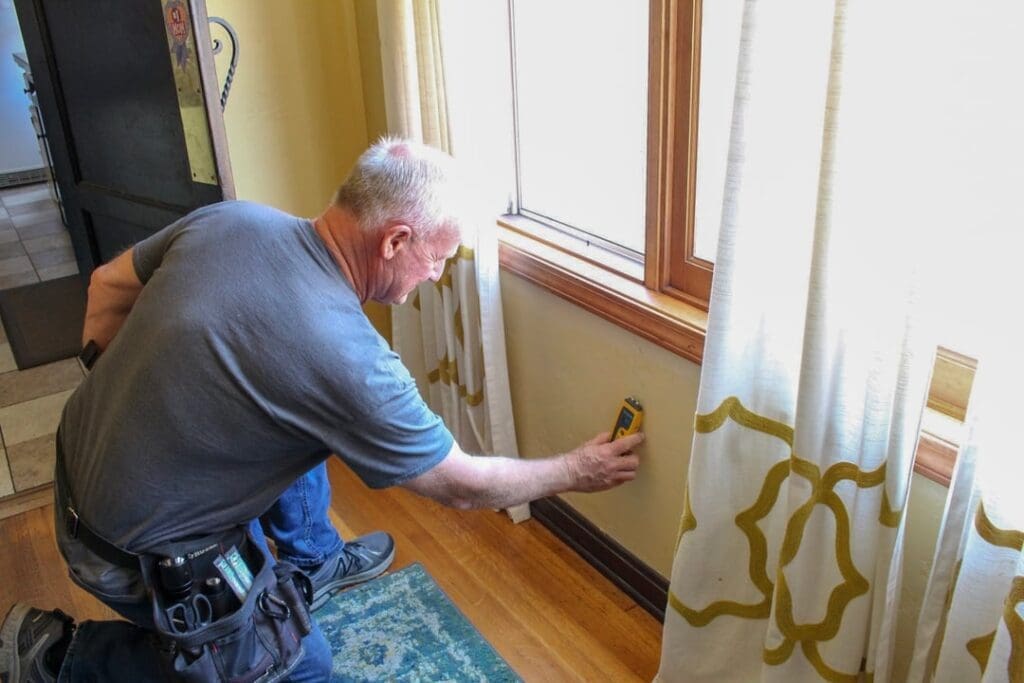 mold inspector detecting mold on a wall with mold detector meter.