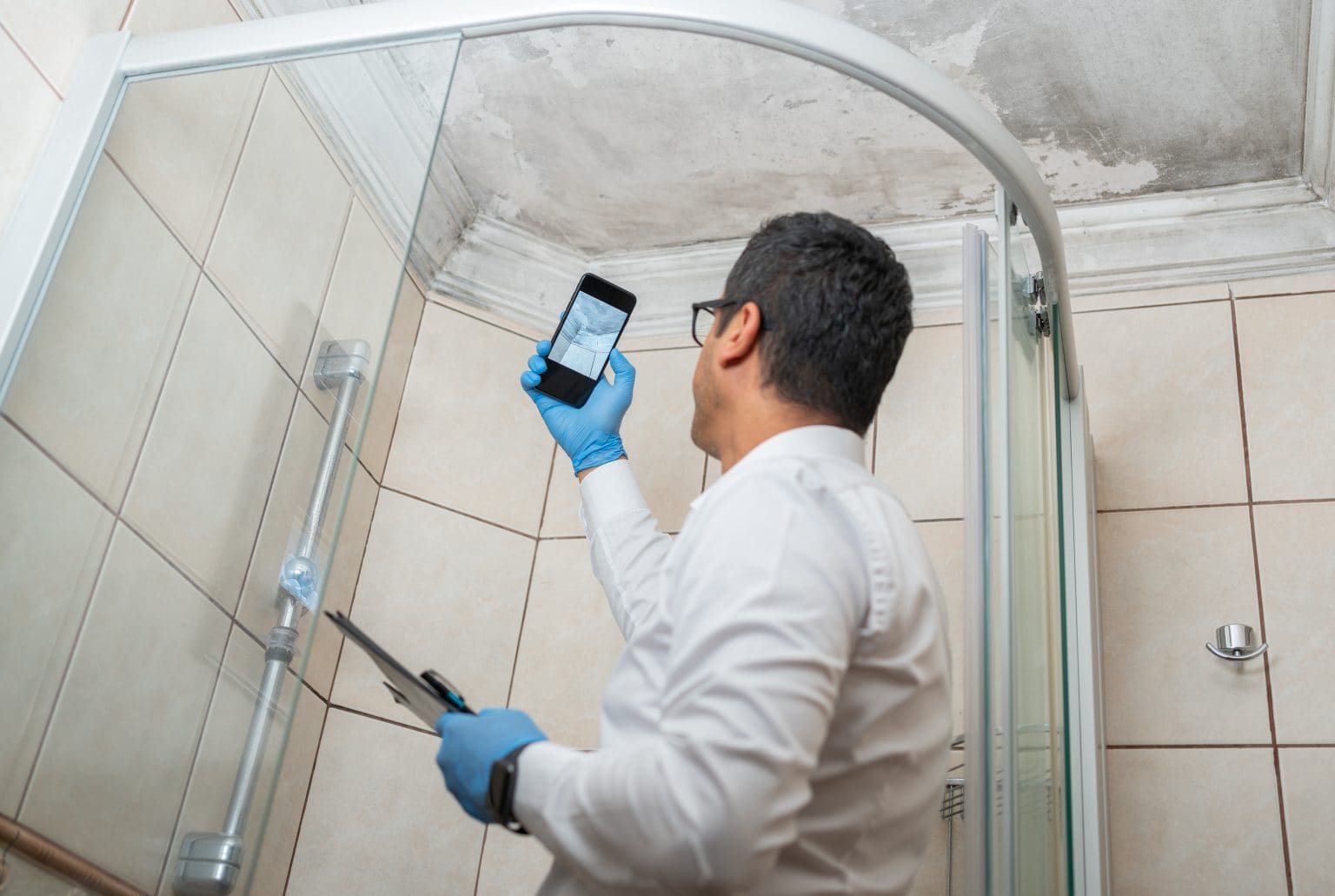 mold remediation expert taking picture of mold on roof of the bathroom.